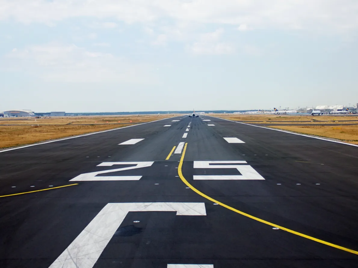 A runway with the airport in the background to its right